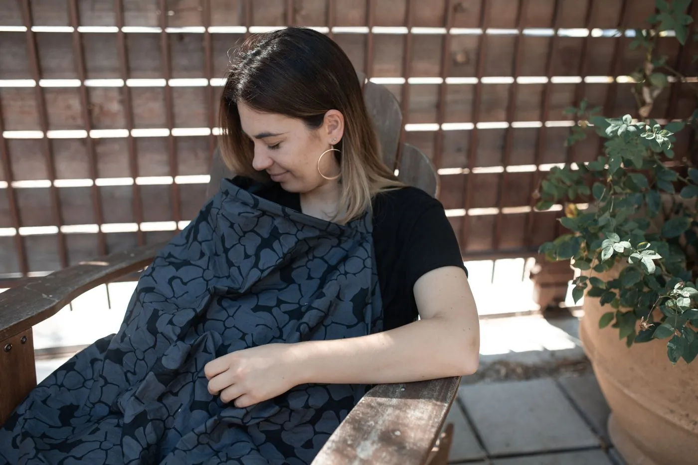 Matka venku kojí miminko pod stylovou kojicí plachtou