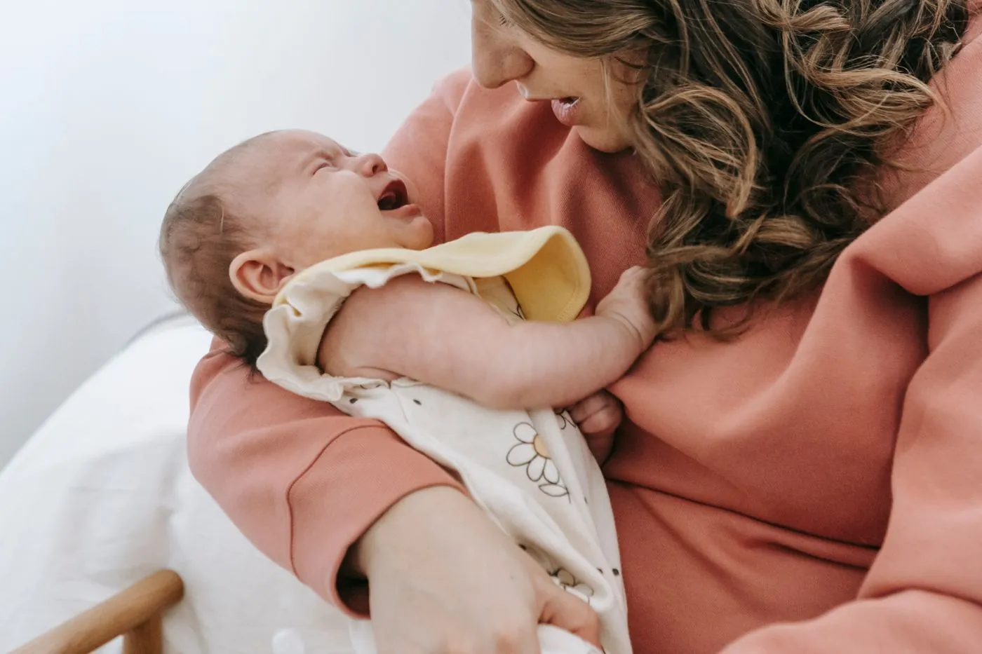 Maminka utišuje plačící miminko v teplém objetí