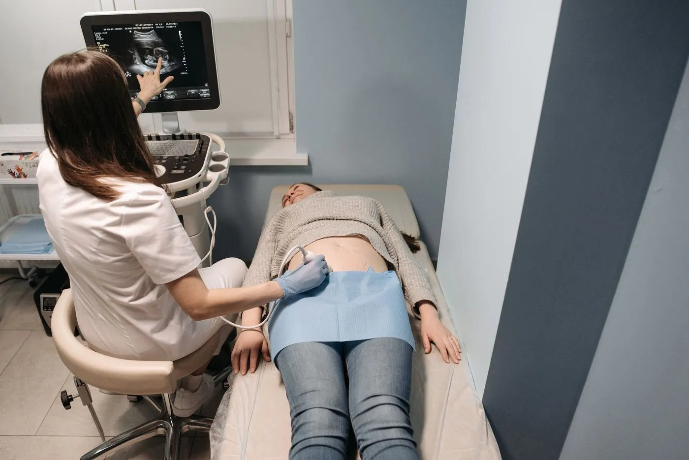 Zdravotní sestra provádí ultrazvukové vyšetření těhotné ženě na lehátku